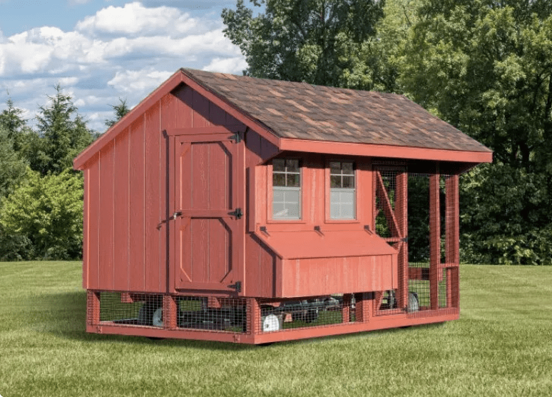 A large red Amish built chicken coop sitting on beautifully manicured grass pasture.