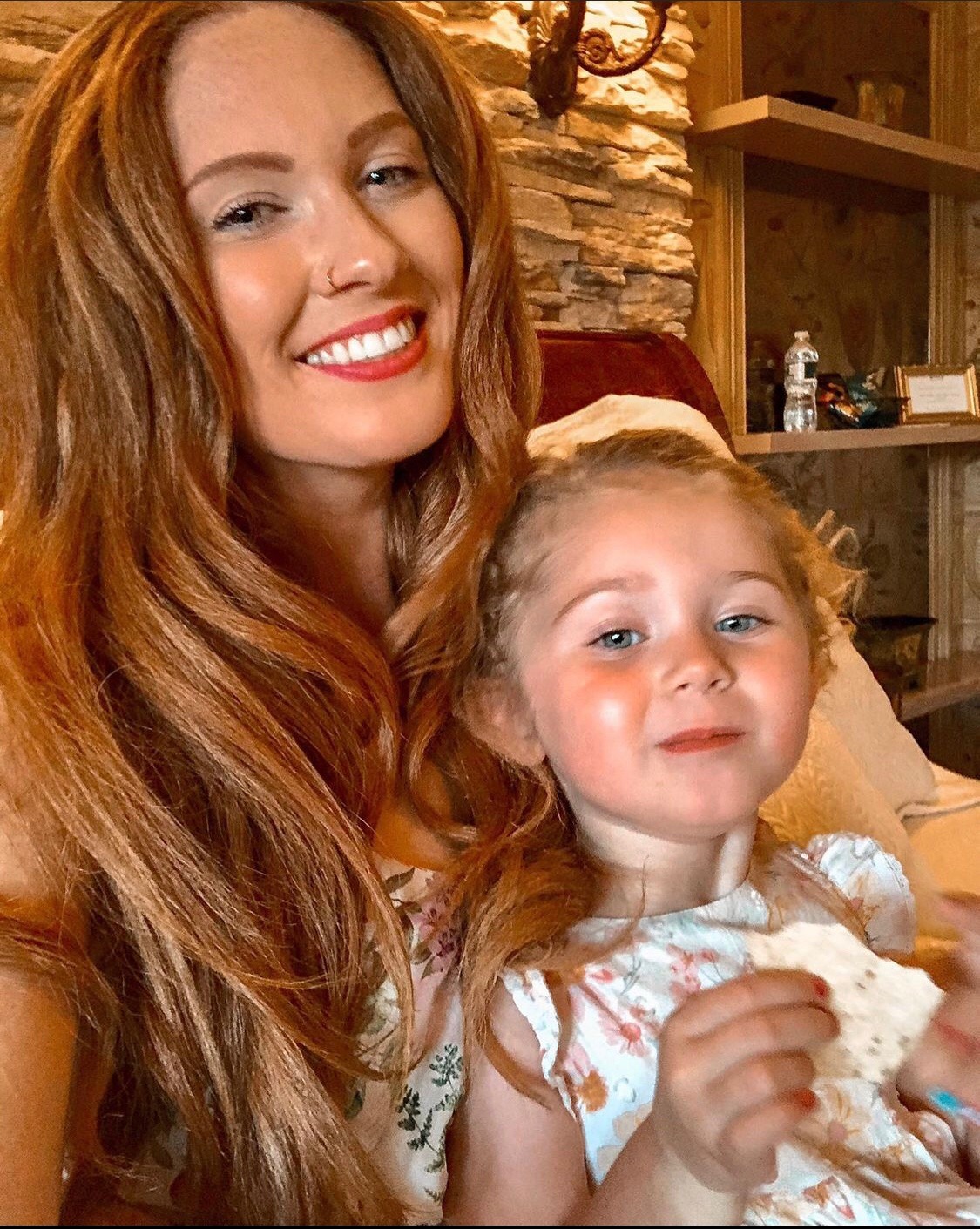 redhead smiling with a toddler sitting on her lap.