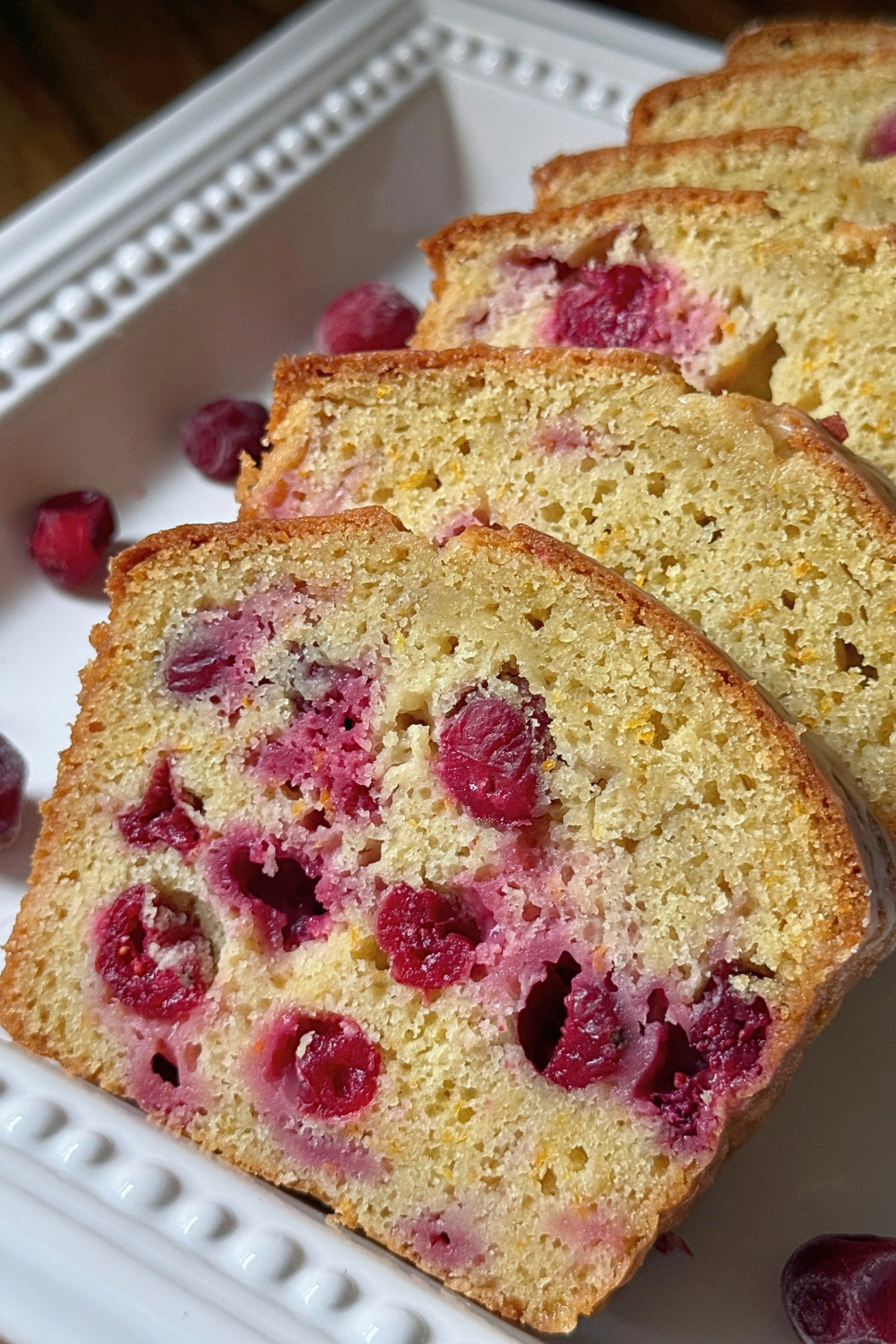 Slices of cranberry orange bread showing whole cranberries throughout the loaf